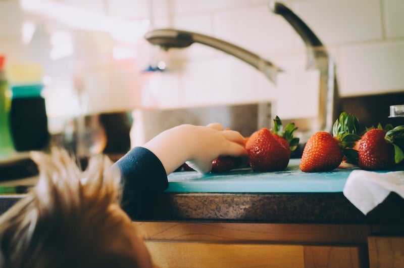 Rinsing fresh strawberries under a kitchen faucet