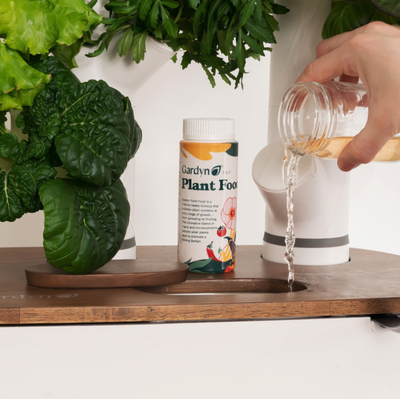 Adding Gardyn Plant Food liquid nutrients to water tank for healthy plant growth
