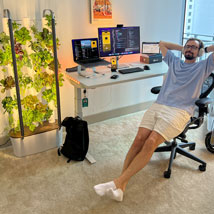 A professional man, Dima Osadchy, seated at a desk next to a Gardyn Home System, creating a serene and productive workspace.